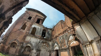 Ancient palace ruins with intricate carvings and weathered brick architecture overgrown with...