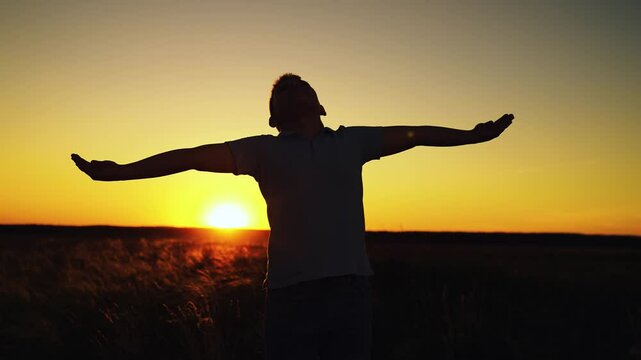 Little boy prays against background of sky, sun. Religion and god. Child boy plays in park against sky. Boy Child raised his hands to sky in park at sunset, childhood dreams. Happy family. True faith