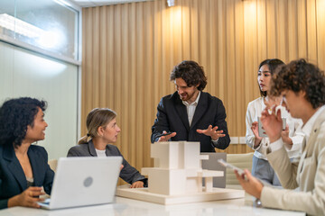 Architects engineers collaborating on building design project in modern office, diverse team of professionals female muslim architect and male engineers discussing architectural model of structure
