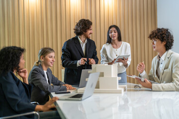 Architects engineers collaborating on building design project in modern office, diverse team of professionals female muslim architect and male engineers discussing architectural model of structure