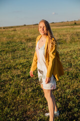 Portrait of a woman in a summer dress on a green field at sunset