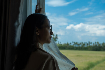 The housekeeper is arranging the curtains and cleaning the windows of the resort bedroom