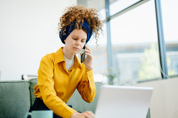 Portrait of a woman using laptop and tablet while sitting on a Green couch at home office