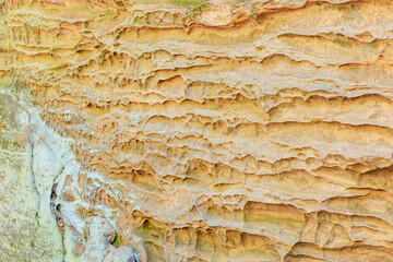 Eroded sandstone wall with natural texture and layers in sunlight