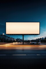 A large billboard is lit up at night, with a blurry bus in the background
