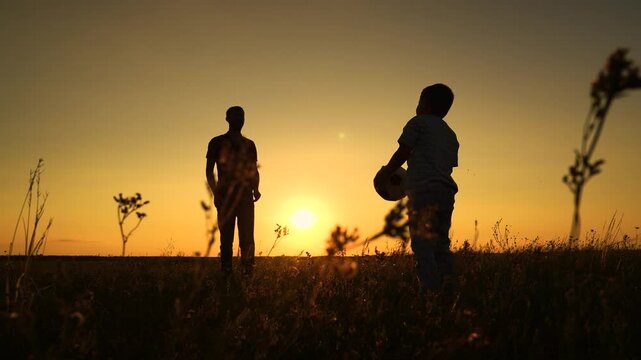 Happy active family play ball. Father throwing ball to child son in summer park, educational game having fun nature. Father son playing ball at sunset summer meadow, slow motion. Dad together with son