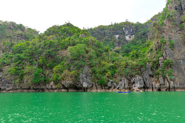 Fototapeta premium Ha Long Bay littered with mountains and Rock cliffs popping out of the ocean, lush green mountains in Vietnam
