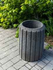 A large stone trash can sitting on a brick walkway