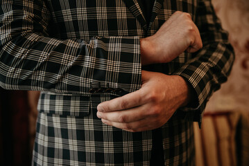 Male model or groom on his wedding day holding the sleeve of a stylish modern fashionable jacket