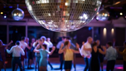 Disco ball hanging in a nightclub reflecting colored lights. Party with many people.
