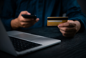 Hand holding credit card and mobile phone for online payment. Digital finance transaction and banking concept for shopping or mobile purchase through e-commerce platforms.