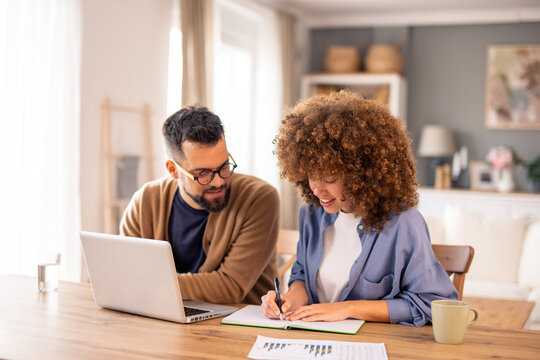 Diverse Professional Couple Collaborating On Project At Home Office With Laptop And Financial Documents