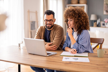 Smiling Couple Collaborates on a Laptop in a Cozy Modern Home with Warm Natural Lighting