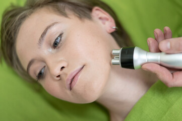 Top view of Caucasian woman undergoing radio wave RF lifting procedure in beauty salon. 