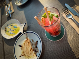 Strawberry Mojito cocktail with straws and two empty plates at a restaurant