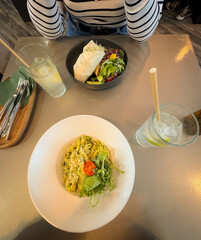 Lunch break with a friend table top view with pasta pesto dish and healthy wraps with refreshing citrus drink on the side