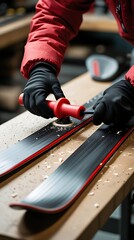 Person tuning skis by waxing the base with a hot iron tool, wearing gloves and winter jacket in a workshop setting, preparing ski equipment for optimal performance on snow

