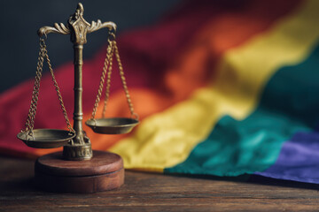 Fototapeta na wymiar Scales of justice positioned against a blurred rainbow flag, symbolizing LGBTQ+ rights and the pursuit of equality and fairness in legal systems. : Generative AI