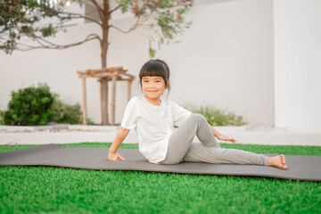 Close-up little asian child girl doing yoga in the public park. 
