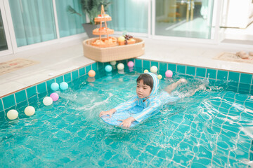  little girls swimming in swimming pool,they children so happy,bright sunlight,sunny day