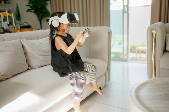 Relaxation concept, Young little girl in VR glasses and controls the joystick to playing exciting games 
