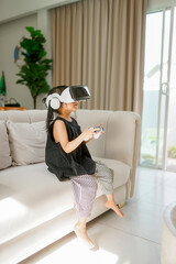 Relaxation concept, Young little girl in VR glasses and controls the joystick to playing exciting games 
