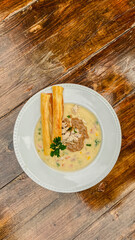 A delightful creamy soup with vibrant herb garnish, paired with a crunchy breadstick on a beautifully textured wooden table.