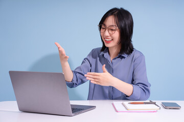 Young Asian woman engaging in a virtual meeting while working from home in a well-lit room
