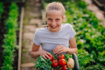 Young farmer girl holding fresh vegetables in orchard