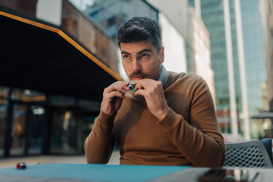 Businessman preparing snus outdoors at a cafe table