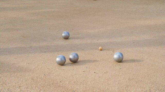 Silver boules lying on sandy terrain with small wooden cochonnet in french petanque game. 