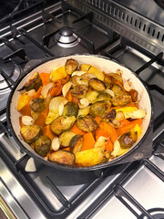 Roasted Vegetables: Potatoes, Pumpkin, Carrots, Garlic, and Brussels Sprouts in Cast Iron Skillet. Vegetable-Based Homemade Food Concept. Handmade Mobile Photo, Selective Focus, Not AI