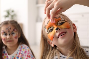 Animator drawing fox on girl's face indoors, closeup
