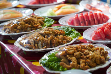 Fruits and food are placed on plates and wrapped in plastic on the dining table.