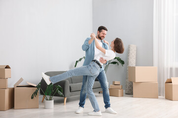 Moving day. Happy couple dancing in their new home