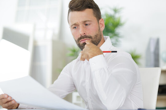 thoughtful or skeptical businessman looking through online statistics