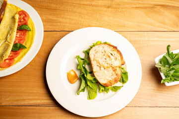 Top view of classic vegetarian and cheese sandwich served with a dip on a white plate, placed on a brown restaurant table for a simple and inviting café-style presentation.