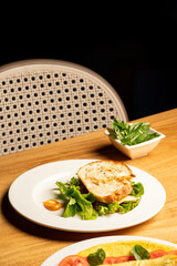 Classic vegetarian and cheese sandwich served with a dip on a white plate, placed on a brown table in a restaurant setting for a comforting and casual café-style meal presentation