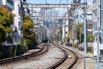 Fototapeta premium View over length of the railroad tracks in middle of residential area in Tokyo, Japan with in distance one person crossing the tracks at the crossing