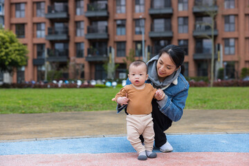 Mother holding baby learning to walk inside