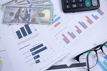 Financial charts, cash, calculator, and glasses on a desk, representing business analysis and...