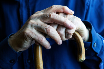 Elderly Hands Holding a Wooden Cane Indoors for Support