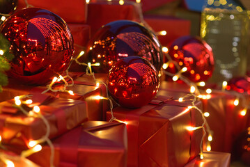New Year gifts in red paper and red toy balls, lights bokeh in the background, merry christmas, shallow depth of field