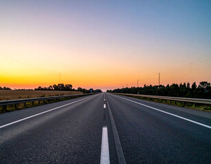 serene highway stretches into horizon, framed by fields and trees under colorful sunset sky. peaceful atmosphere invites sense of adventure and exploration