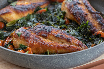 delicious cooked chicken breast with spinach and cherry tomatoes in a pan
