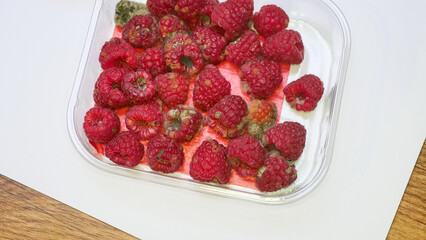 Moldy raspberries close-up on white background, expired products, consumer protection, health hazard, rot, detail, berries