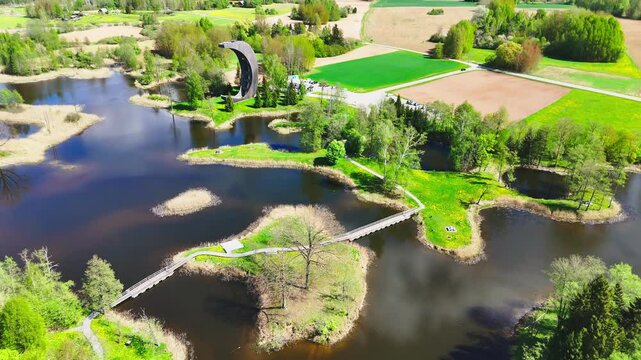 Biržai Regional Park, Lithuania - The Crescent-shaped Kirkilai Observation Tower Provides a View of the Karst Lakes, Meandering Bridges, and Verdant Vegetation - Drone Flying Forward