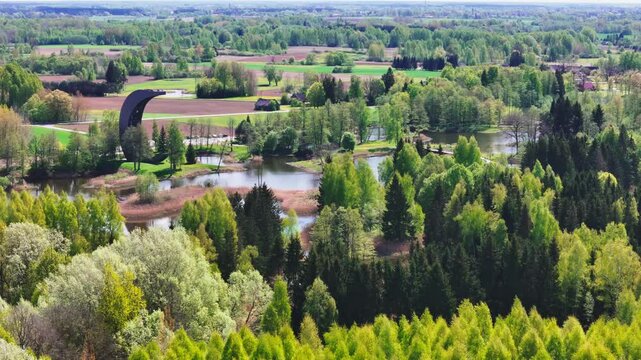 A Magnificent View Shows the Kirkilai Observation Tower Overlooking the Karst Lake and Dense Flora in Biržai Regional Park, Lithuania - Orbit Drone Shot