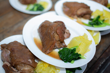 Stewed pork leg placed on several white plates on a wooden background.