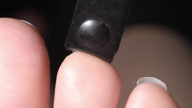 Low-angle close-up showing small toes having nails trimmed with a black clipper tool
